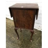 A walnut cupboard, the moulded top with two drop leaves, raised on cabriole legs.