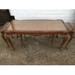 A nest of three walnut coffee tables with plate glass tops in leaf carved frames, supported on