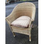 A cane armchair with rounded back and loose cushion to seat, raise on bound legs.