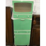 A 60s painted kitchen cabinet with glass door above a drawer and fallfront formica work surface,