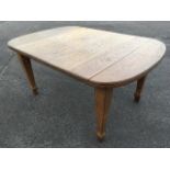 A telescopic Edwardian oak dining table, the moulded top with rounded ends supported on square