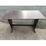 A rectangular table with press carved rim, supported on tapering trestle style supports joined by