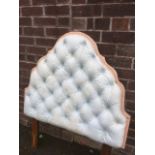 A quilted cotton headboard of arched shape with button upholstery.