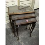 A nest of three mahogany tables, the tray tops with carved mouldings and knees, on slender