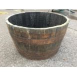 An oak garden barrel tub planter, the staves bound by three metal strap bands.