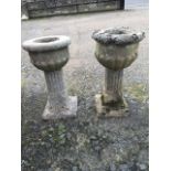 A pair of antique sandstone urns on columns, the fluted pots with ropetwist rims, the supports on