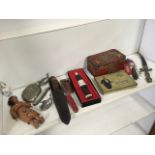 A miscellaneous box containing knives, an Indian doll, tins, a clockwork fish, pewter, a porcelain