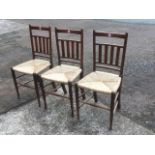 A set of three William Birch rush seated chairs, the rounded backs with slats, raised on ring-turned