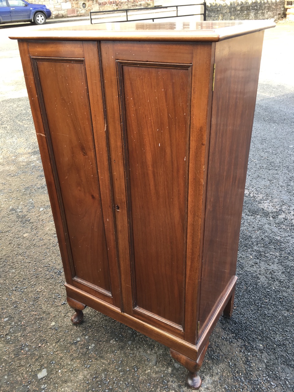 A mahogany cabinet with panelled doors enclosing shelves, raised on stub cabriole legs.