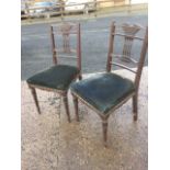 A pair of Edwardian mahogany chairs, the backs with slender spindles beneath scrolled rails,