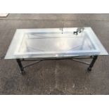 A rectangular glass topped coffee table, the bevelled plate above aprons wrought with swags &