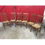 A set of six Liberty oak dining chairs, the back rails pierced with heart motifs above rush seats,