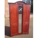 A mahogany double wardrobe with arched moulded cornice above a central mirror flanked by panelled