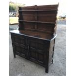 An oak dresser, the panelled back with two grooved shelves and shaped sides, above a base with