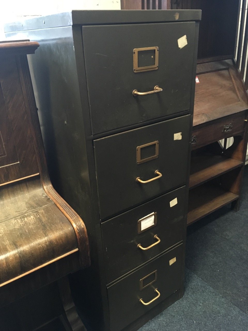 A metal filing cabinet with four drawers mounted with tubular handles.