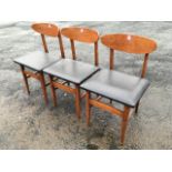 A set of three Gplan style dining chairs with elliptical backs above upholstered seats, raised on