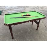 A folding pool table, the baize lined top with brass pockets, complete with cues, balls, triangle,