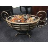 An oval wrought iron fire basket, the cage mounted with scrolled handles, fitted with a twin-bar