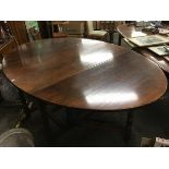 A large oak gateleg table, the oval top with frieze drawer and two drop leaves, raised on baluster