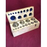 A hardwood cased set of brass weights, the set from 1kg to 1grm, complete with tweezers.