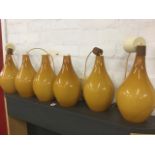 A suite of six 60s pendant lights, the amber bottle shaped glass shades with hardwood mounts,