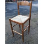 A tall bar stool with arched back on turned columns with ball finials, having square rush seat on