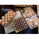 A boxed chess/draughts set in hinged inlaid box; a hardwood chess board; and a cased backgammon set.