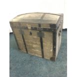 A domed top seamans chest with slatted wood & metal mounts, having twin brass locks and carrying