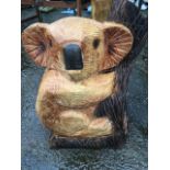 A carved koala bear, cut a from a single piece of douglas fir, with scorched and painted decoration.