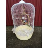 A tubular wirework parrot cage, with ring, feeders, carved & painted wood bird, etc.