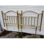 A pair of brass plated single bedheads, with arched rails above columns, the cornerposts with ball