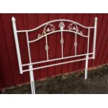 A wrought iron bedhead, the arched frame with scrolled decoration having fluted flowerhead finials