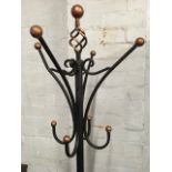 A wrought iron coatstand, with four scrolled pegs around a column with twisted ball finial,