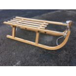 A beech sledge with metal runners and slatted seat.