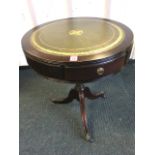 A circular drum table with gilt tooled skiver to reeded top above three frieze drawers, supported on