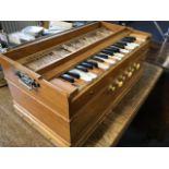 A walnut cased harmonium with bellows, having stops below keyboard, mounted with carrying handles to