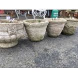 A pair of composition stone garden pots with embossed foliate scrolled decoration; and two