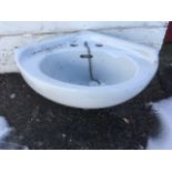 A small corner ceramic hand basin with rounded front and integral overflow.