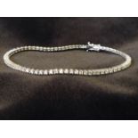 A fine 18K white gold tennis bracelet, set with seventy three claw set hinged diamonds weighing