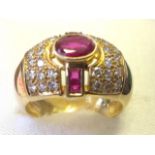 An 18ct gold ruby & diamond dress ring, the oval bezel set princess cut ruby framed by twin baguette