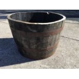 A large garden barrel tub, the oak staves bound by three metal strap bands.