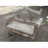 A wrought iron garden bench, the arched back with oval palm tree medallion above scrolled grill,