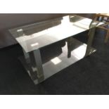 A modern glass coffee table, with two platforms on rectangular metal supports.