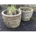 A pair of circular composition stone garden pots moulded with friezes of stags & vines. (2)