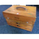 A dovetailed pine box with leather handles and three drawers.