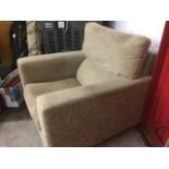 A square shaped upholstered armchair, with loose cushion and platform arms raised on bun feet.