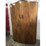 A 60s bowfronted walnut wardrobe with arched doors enclosing shelf & hanging space, supported on a