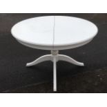 A circular dining table with integral leaf raised on column with quadripartite splayed legs.