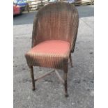 A lloyd loom style chair with hooped back above seat with plain apron, raised on turned legs