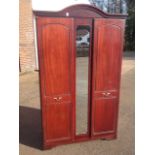 A mahogany wardrobe with arched moulded cornice above a central mirror flanked by panelled doors